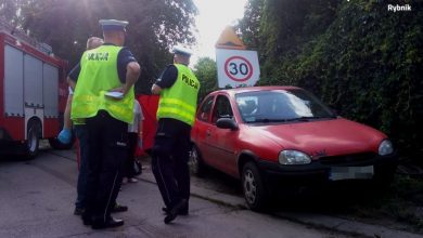 Na zdjęciu czerwony Opel Corsa, oraz policjanci zabezpieczający miejsce wypadku, w którym w Rybniku-Kamieniu zginął 7-letni chłopiec