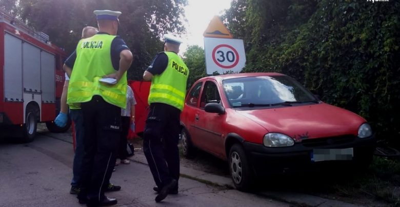 Na zdjęciu czerwony Opel Corsa, oraz policjanci zabezpieczający miejsce wypadku, w którym w Rybniku-Kamieniu zginął 7-letni chłopiec
