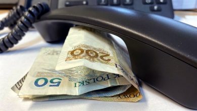 słuchawka telefonu leży na stoliku przy niej banknoty pieniędzy, w tle telefon z klawiaturą