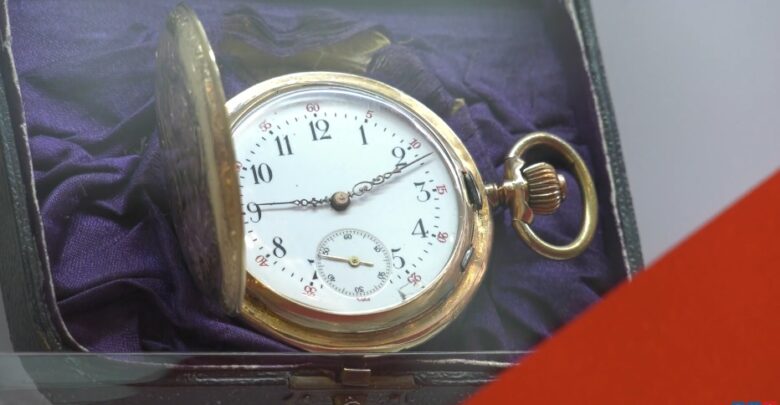 Na zdjęciu stary, złoty zegarek, obrócony o 90 stopni w prawo, złoty, z dewizką