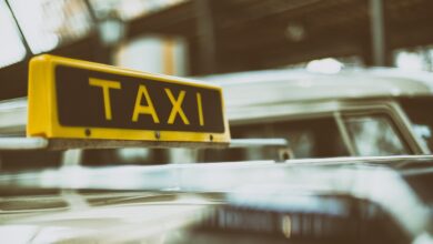 Żółty znak TAXI na czarnym tle, umieszczony na dachu samochodu