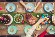 savoir-vivre przy wielkanocnym stole zastawionym potrawami. Widoczne ręce gości obierające jajka