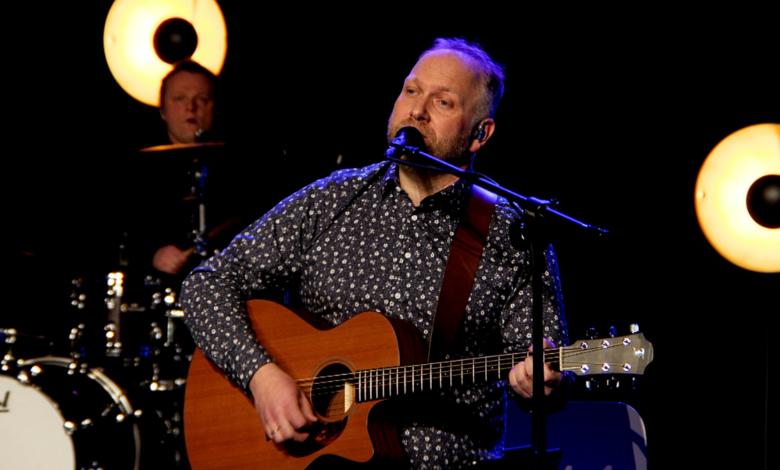 Mateusz Szymczyk - mężczyzna na scenia z gitraa śpiewa piosenkę