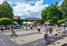 Piknik Bezpieczny Powiat pszczyna, dzieci na rowerach i dorośli instruktorzy na terenie miasteczka ruchu drogowego