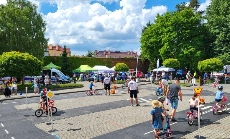 Piknik Bezpieczny Powiat pszczyna, dzieci na rowerach i dorośli instruktorzy na terenie miasteczka ruchu drogowego
