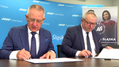 Koleje Śląskie współpraca z Akademią Śląską dwaj mężczyźni przy stole podpisują dokumenty.