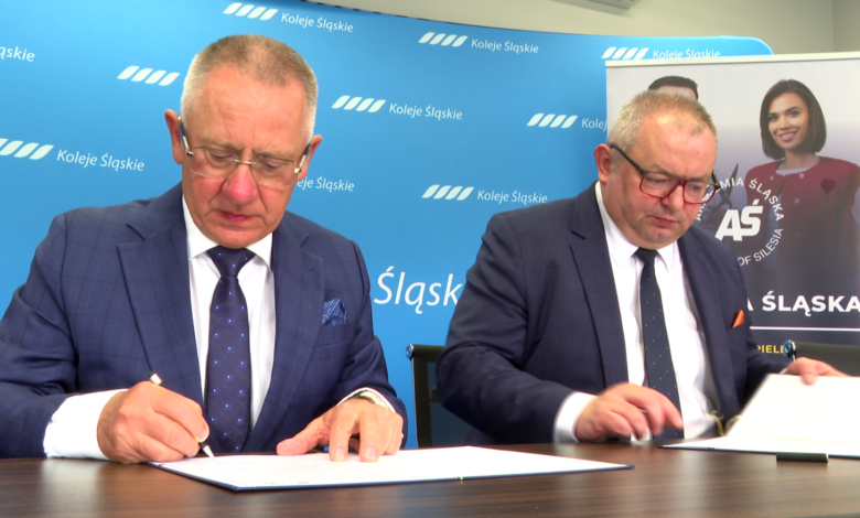 Koleje Śląskie współpraca z Akademią Śląską dwaj mężczyźni przy stole podpisują dokumenty.