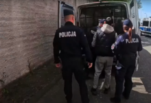 Handel Ludźmi Katowice policjanci prowadzą zatrzymanego mężczyznę do samochodu