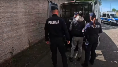 Handel Ludźmi Katowice policjanci prowadzą zatrzymanego mężczyznę do samochodu