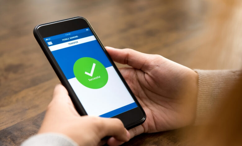 przelew z ZUS na konto Ekran telefonu komórkowego z aplikacja bankową trzymany w rękach