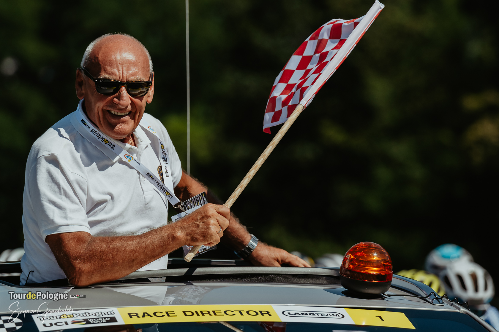 Tour de Pologne mężczyzna z flagą startową w odkrytym samochodzie