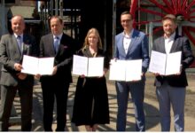 Kopalnia Wujek porozumienie grupa osób pozując do zdjęcia z dokumentami w dłoniach