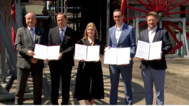 Kopalnia Wujek porozumienie grupa osób pozując do zdjęcia z dokumentami w dłoniach