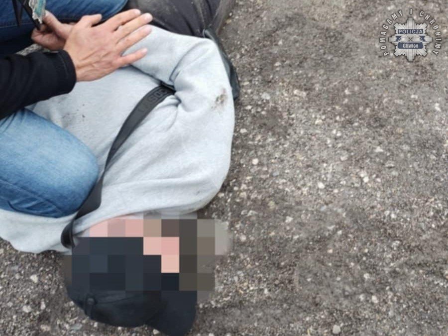 kradzieże samochodów Śląsk - mężczyzna zatrzymany lezy na ziemi trzymany przez policjanta