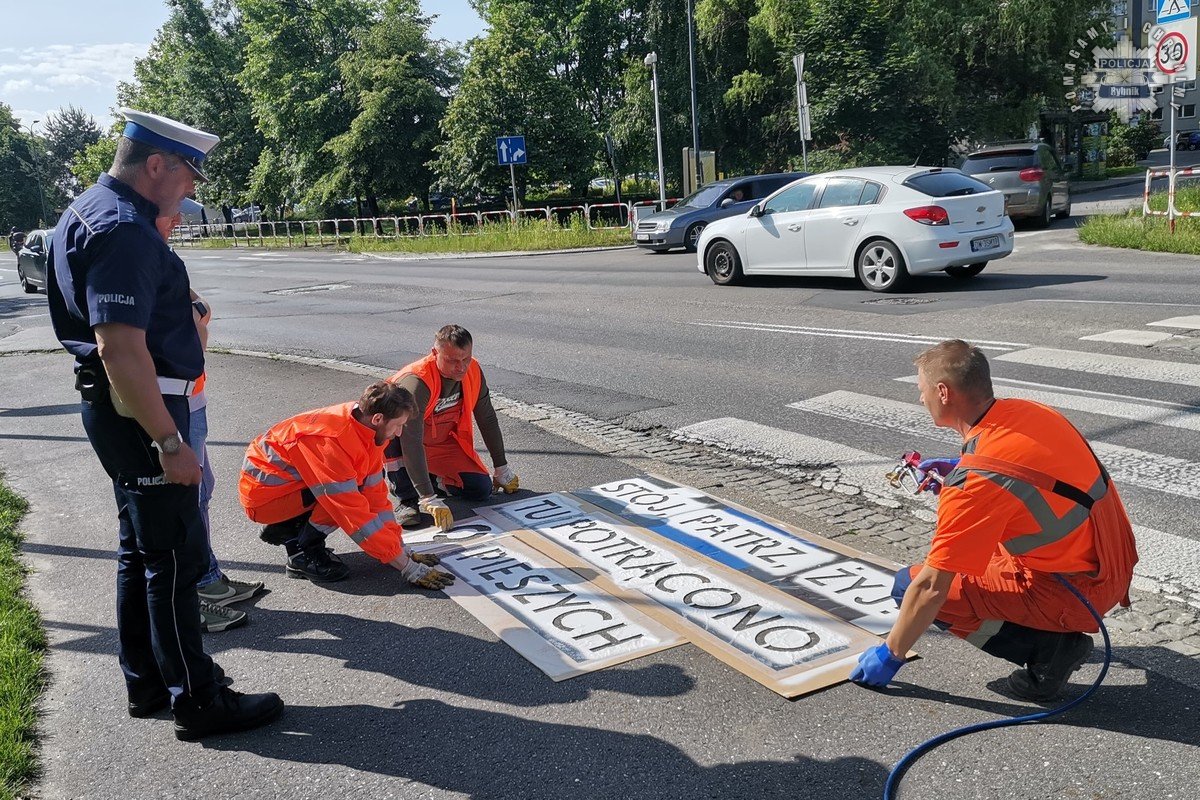 kampania Stój patrz żyj mężczyźni malują hasła na chodniku