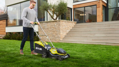 Mężczyzna z akumulatorową kosiarką RYOBI kosi trawę przed domem