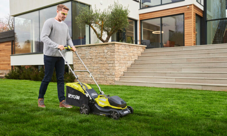 Mężczyzna z akumulatorową kosiarką RYOBI kosi trawę przed domem
