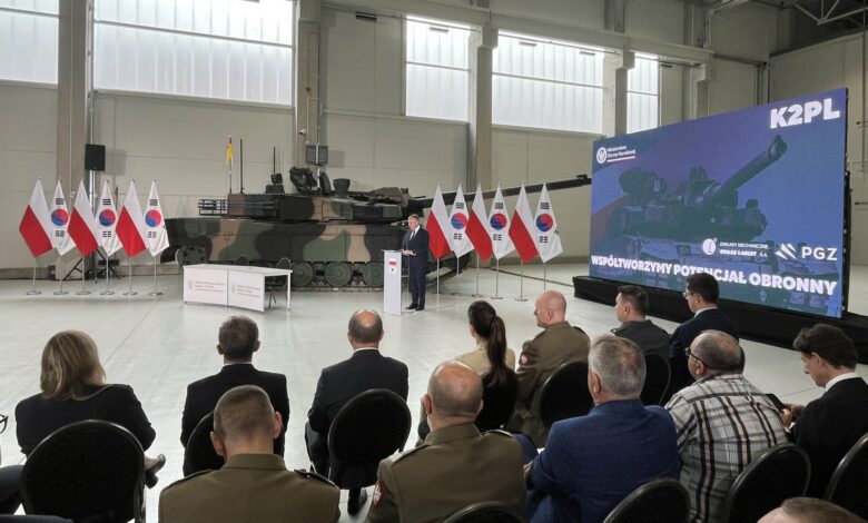 czołgi K2PL produkowane w Gliwicach hala w tle czołk i flagi białoczerwone, grupa osób podczas uroczystego spotkania