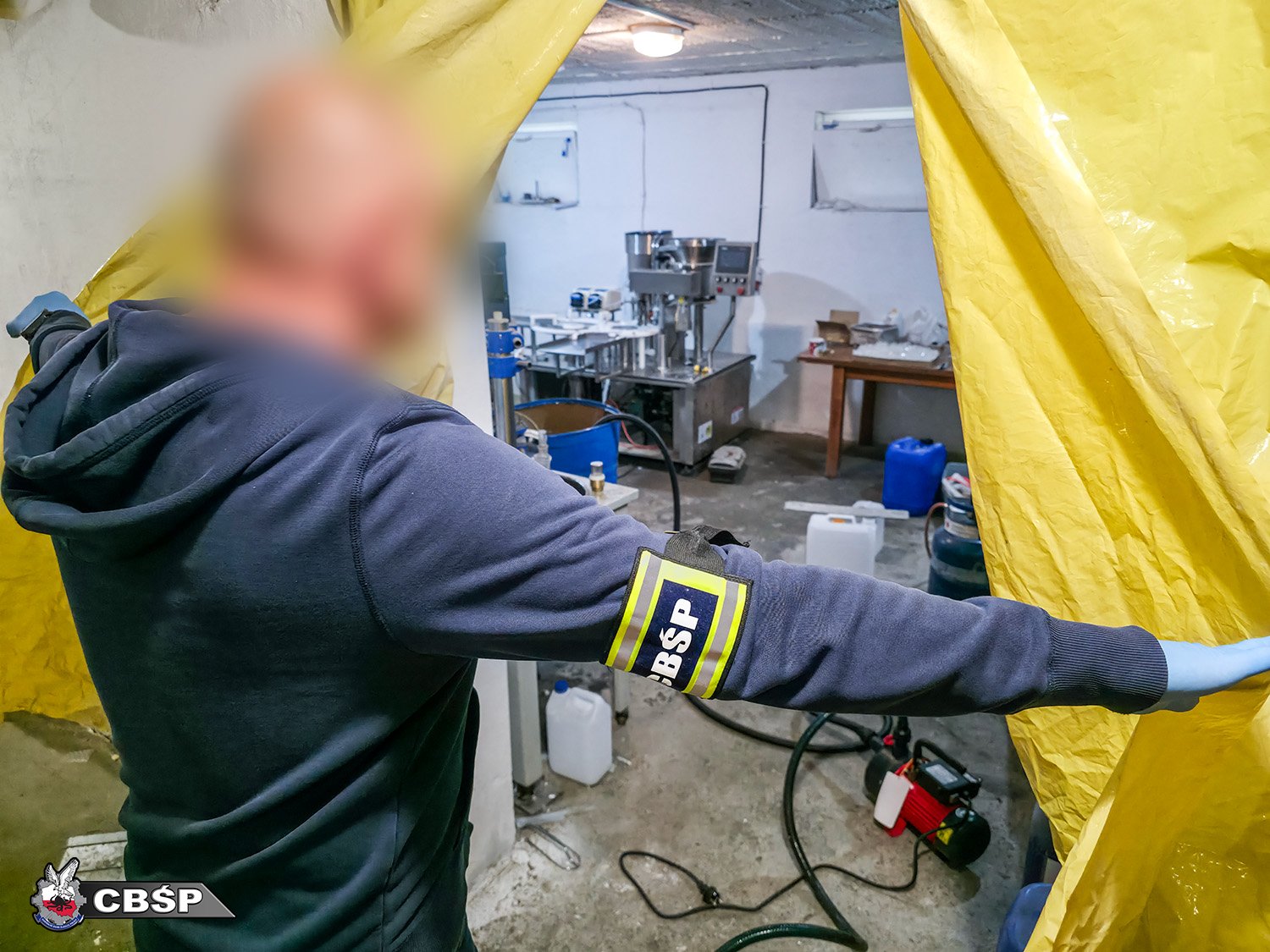 Policjant wchodzi do pomieszczenia i odsłania kotarę