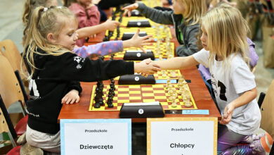 Młodzi ludzie nad szachownicą podają sobie dłonie