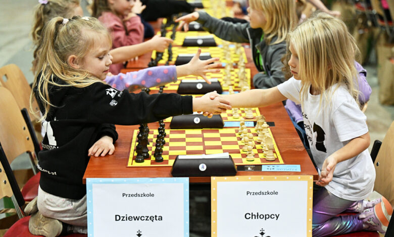 Młodzi ludzie nad szachownicą podają sobie dłonie