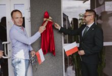 Miniaturowe Rzeźby w Żarkach odsłonięcie rzeźby dwóch męzczyzn zdejmuje ze ściany tkanine zasłaniająca rzeźbę