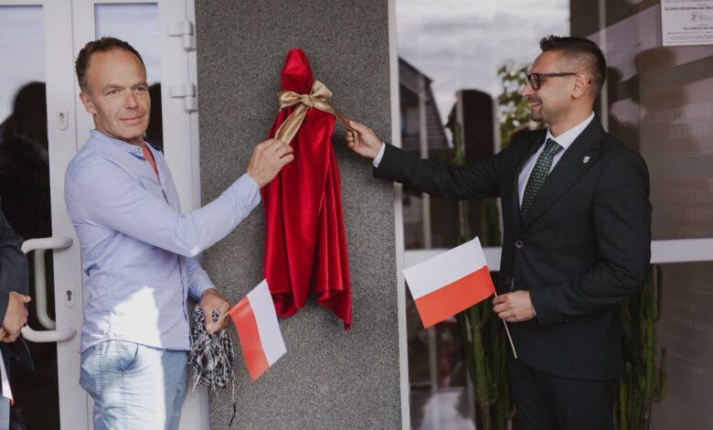 Miniaturowe Rzeźby w Żarkach odsłonięcie rzeźby dwóch męzczyzn zdejmuje ze ściany tkanine zasłaniająca rzeźbę