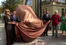 Rzeźba byka Rafała Olbińskiego Katowice gruppa osób zdejmuje płachtę materiału z Byka