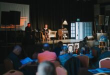 Scena na której na kanapie siedza dwie osoby fragment widowni z widzami