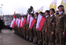 W szerwgu grupa dziewczyn w mundurach każda trzyma flagę