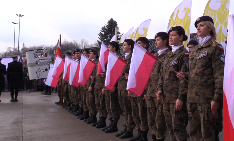 W szerwgu grupa dziewczyn w mundurach każda trzyma flagę