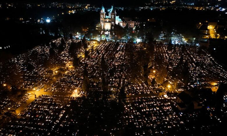 Wszystkich Świętych zmiany w organizacji ruchu w Katowicach - cmentarz nocą z lotu ptaka . widoczny podswietlony kościół i mnóstwo punktów światła płónących zniczy