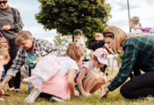 Dzieci i dorośli na trawniku sadzą kwiaty