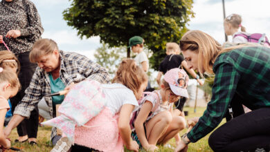 Dzieci i dorośli na trawniku sadzą kwiaty