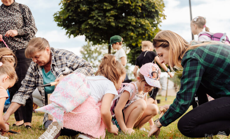 Dzieci i dorośli na trawniku sadzą kwiaty