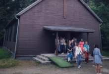 Kościół z drewna a przed nim grupa ludzi