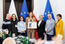 rodziny zastępcze Bielsko-Biała - grupa Osób pozuje do zdjęcia na tle flag unii europejskiej i Polski