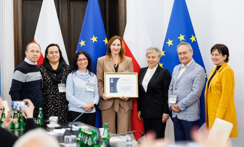 rodziny zastępcze Bielsko-Biała - grupa Osób pozuje do zdjęcia na tle flag unii europejskiej i Polski