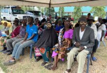 Grupa osób czeka na badnie wzroku, siedza pod baldachimem