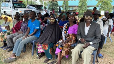 Grupa osób czeka na badnie wzroku, siedza pod baldachimem