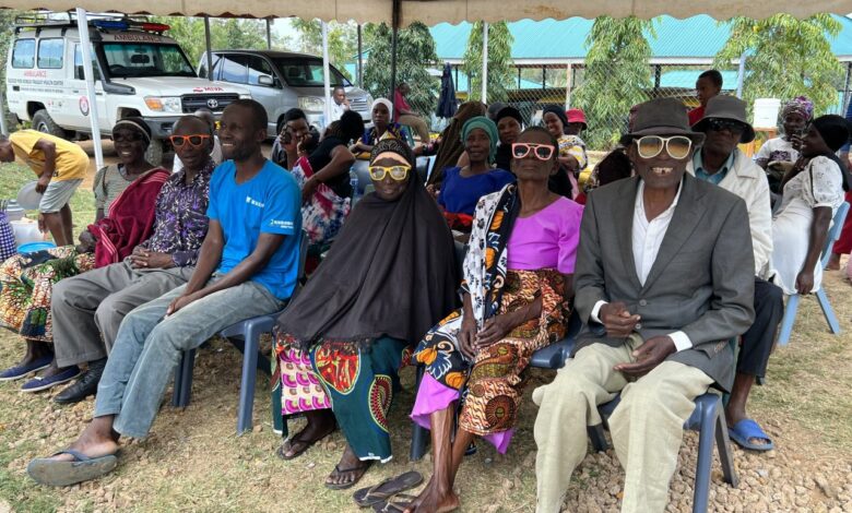 Grupa osób czeka na badnie wzroku, siedza pod baldachimem