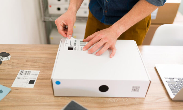 mężczyzna przeklejający etykietę do kartonu