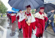 Grupa osób w togach maszeruje ulicą