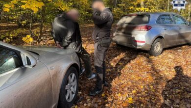 zATRZYMANY ZE SKRĘPOANYMI RĘKOMA Z TYŁU OPIERA SIĘ O MASKĘ SAMOCHODU OBOK STOI POLICJANT