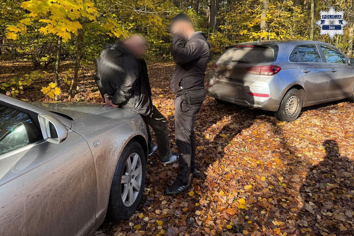 zATRZYMANY ZE SKRĘPOANYMI RĘKOMA Z TYŁU OPIERA SIĘ O MASKĘ SAMOCHODU OBOK STOI POLICJANT